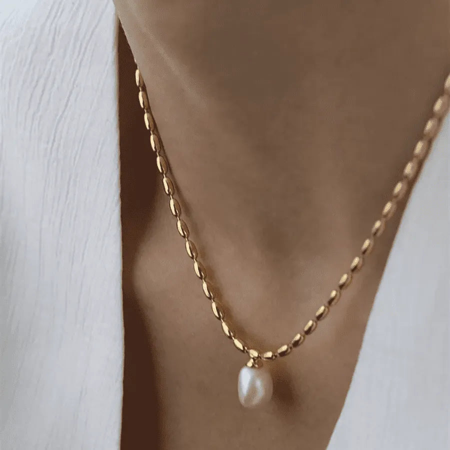 Radiant elegance necklace; Natural pearl necklace; Gold-plated pearl necklace; Pearl and gold jewelry; Elegant pearl necklace; Pearl pendant necklace; Gold chain necklace; Necklace with natural pearl; Timeless pearl jewelry; Luxurious pearl necklace; Pearl jewelry for women; Classic gold and pearl necklace; Sophisticated pearl necklace; 