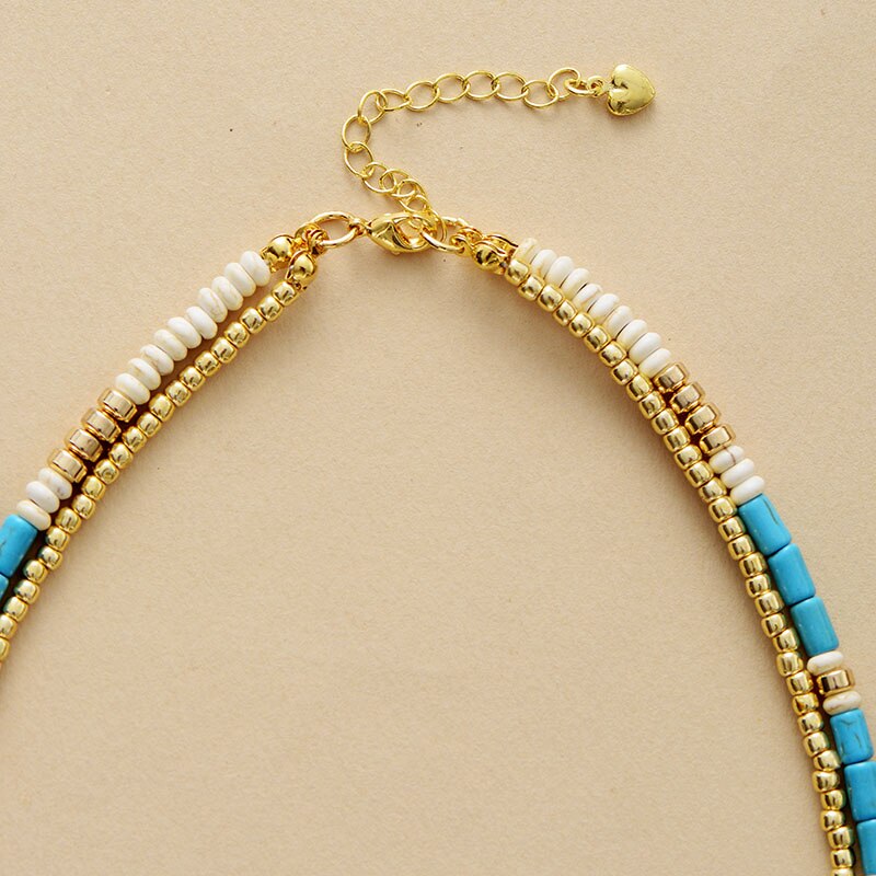 Gold-plated choker necklace; Turquoise and seed accents; Elegant and stylish accessory; Perfect for layering with other necklaces; Unique blend of color and texture; Eye-catching design for any occasion; Ideal gift for fashion enthusiasts; Handcrafted with high-quality materials; Lightweight and comfortable to wear; Durable gold plating for long-lasting shine; Bohemian-inspired jewelry piece; Enhances any outfit with a pop of color; Ethically sourced materials;