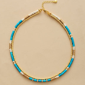 Gold-plated choker necklace; Turquoise and seed accents; Elegant and stylish accessory; Perfect for layering with other necklaces; Unique blend of color and texture; Eye-catching design for any occasion; Ideal gift for fashion enthusiasts; Handcrafted with high-quality materials; Lightweight and comfortable to wear; Durable gold plating for long-lasting shine; Bohemian-inspired jewelry piece; Enhances any outfit with a pop of color; Ethically sourced materials;