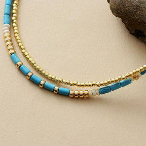 Gold-plated choker necklace; Turquoise and seed accents; Elegant and stylish accessory; Perfect for layering with other necklaces; Unique blend of color and texture; Eye-catching design for any occasion; Ideal gift for fashion enthusiasts; Handcrafted with high-quality materials; Lightweight and comfortable to wear; Durable gold plating for long-lasting shine; Bohemian-inspired jewelry piece; Enhances any outfit with a pop of color; Ethically sourced materials;