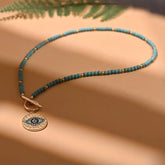 Beach-inspired evil eye necklace; Protective amulet jewelry; Handcrafted beach necklace; Coastal charm necklace; Natural stone beach accessory; Stylish summer jewelry; Boho beach necklace; Unique evil eye pendant; Symbol of protection and luck; Colorful beach-themed necklace; Perfect gift for beach lovers; Trendy ocean-inspired jewelry;