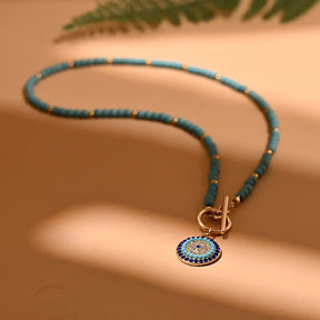 Beach-inspired evil eye necklace; Protective amulet jewelry; Handcrafted beach necklace; Coastal charm necklace; Natural stone beach accessory; Stylish summer jewelry; Boho beach necklace; Unique evil eye pendant; Symbol of protection and luck; Colorful beach-themed necklace; Perfect gift for beach lovers; Trendy ocean-inspired jewelry;